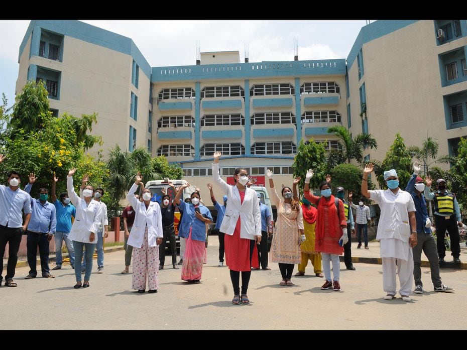 Doctors, nurses and medical staff wave during a fly-past by an Air Force helicopter over the Indira 