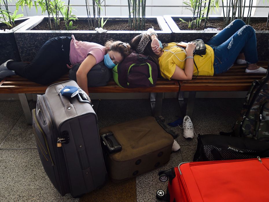 Passengers camp out on a bench outside the Indira Gandhi International Airport in Delhi on the first