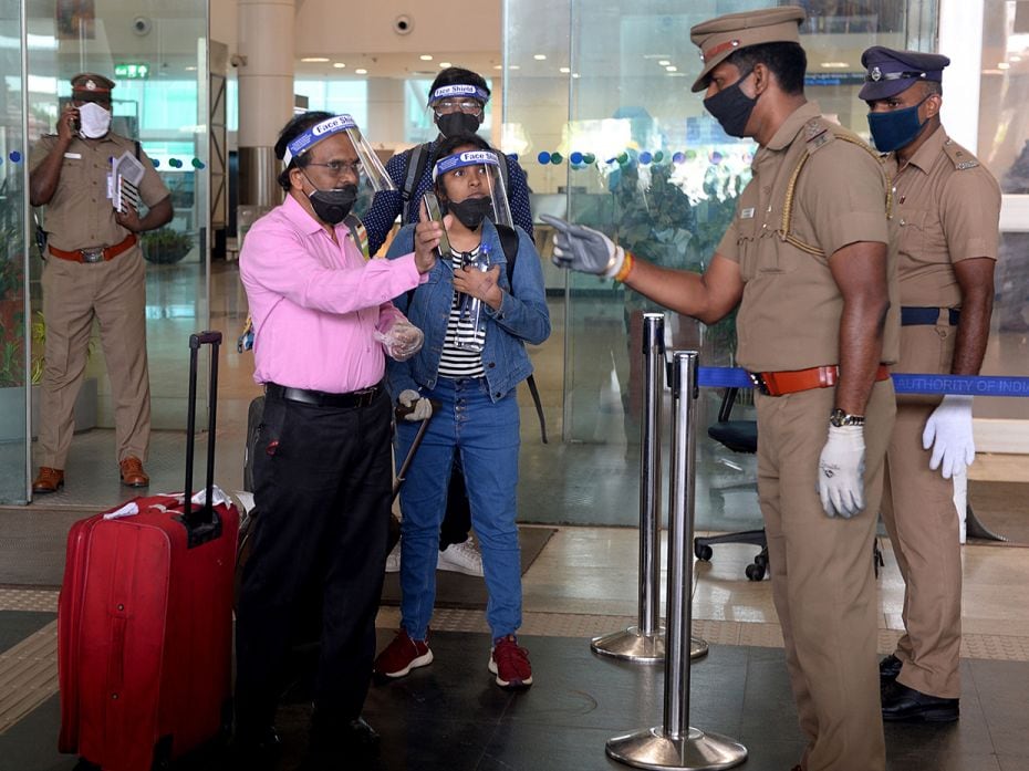 A police officer checks a passenger’s e-pass from afar, when arriving at the Kamaraj domestic 