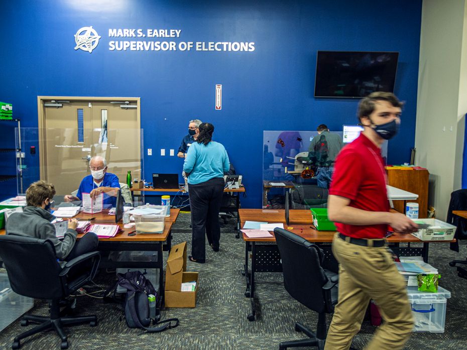 Poll workers in Florida separate mail ballots from their security envelopes for counting on November