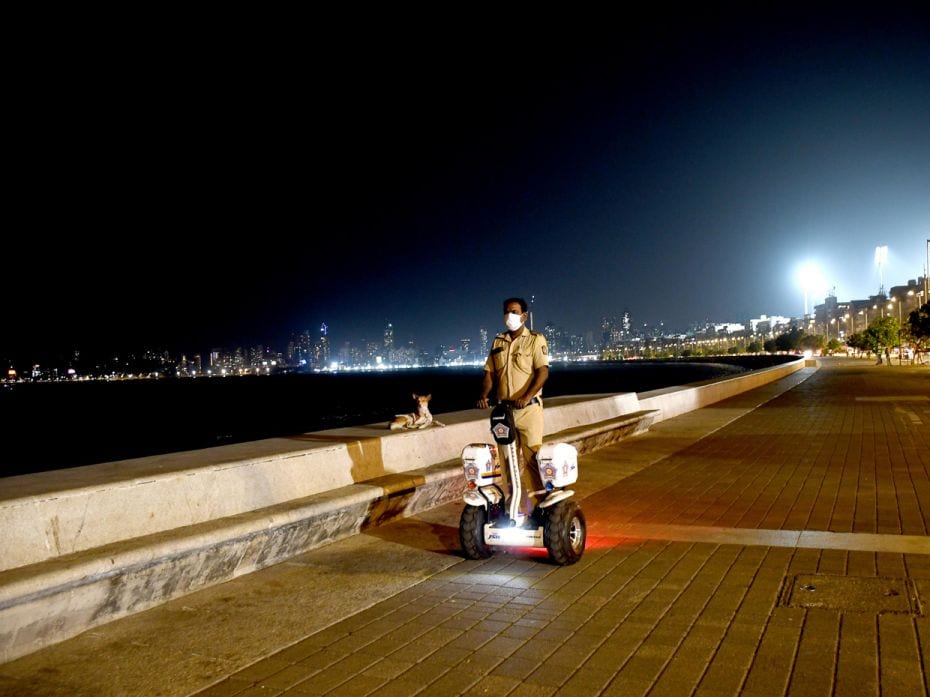 A police officer patrols on a segway scooter on the deserted Marine Drive promenade during the night