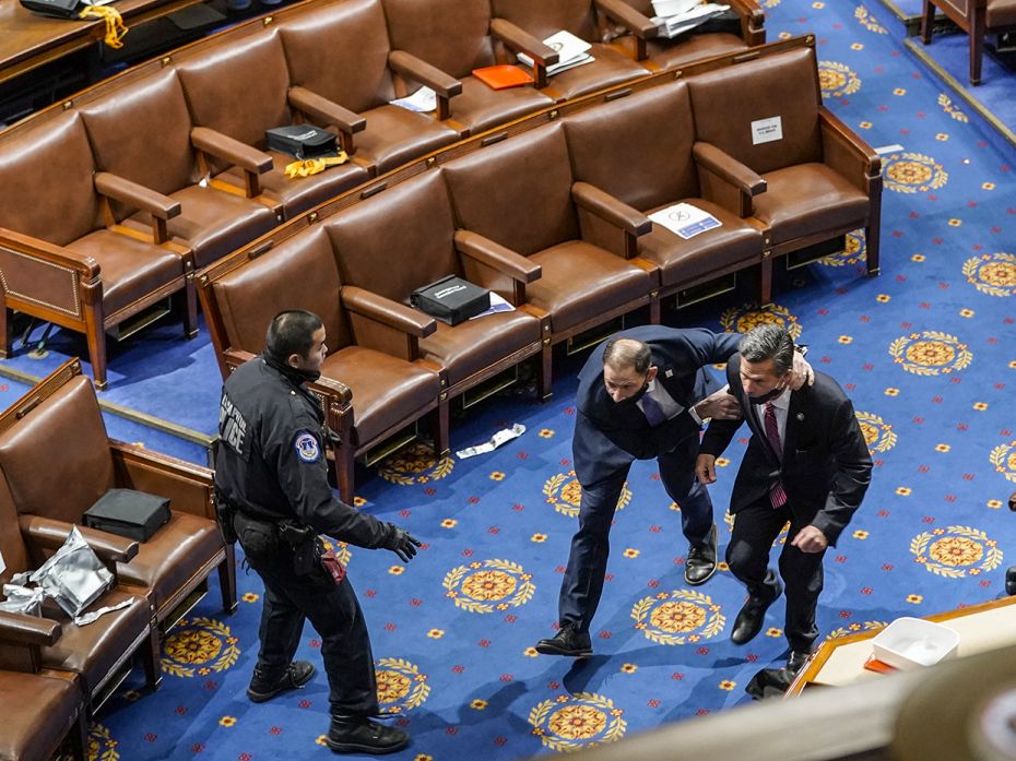 Members of congress run for cover as protesters try to enter the House Chamber during a joint sessio