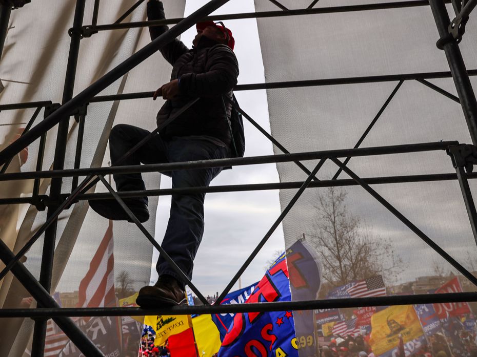 A Donald Trump supporter climbs a scaffolding outside the US Capitol building during a 