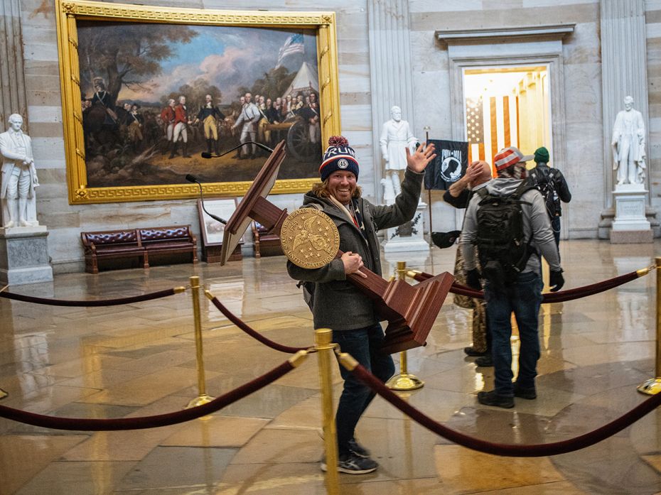 A pro-Trump protester carries the lectern of US Speaker of the House Nancy Pelosi through the Roturn