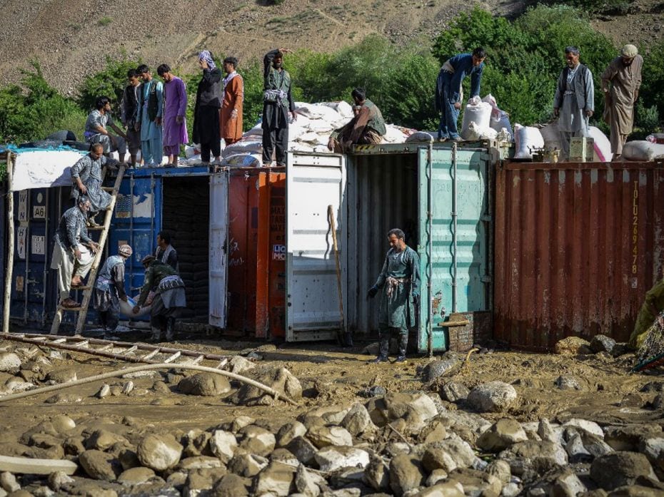 Afghanistan
Afghan shopkeepers secure sacks of flour stored inside containers amid the debris from 