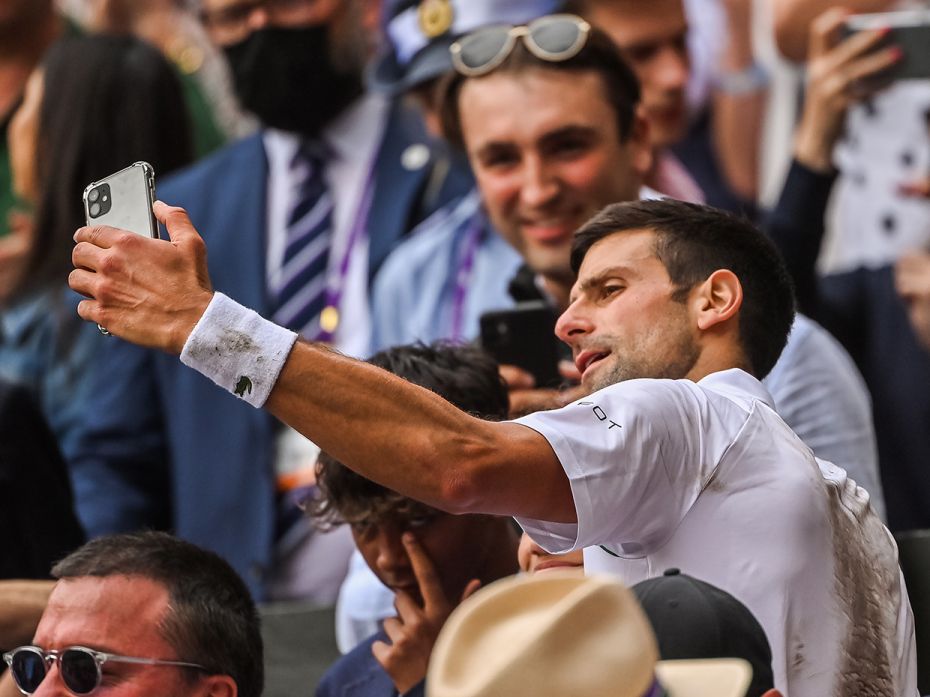 Novak Djokovic of Serbia takes a selfie with a member of the crowd after beating Mateo Berrettini of