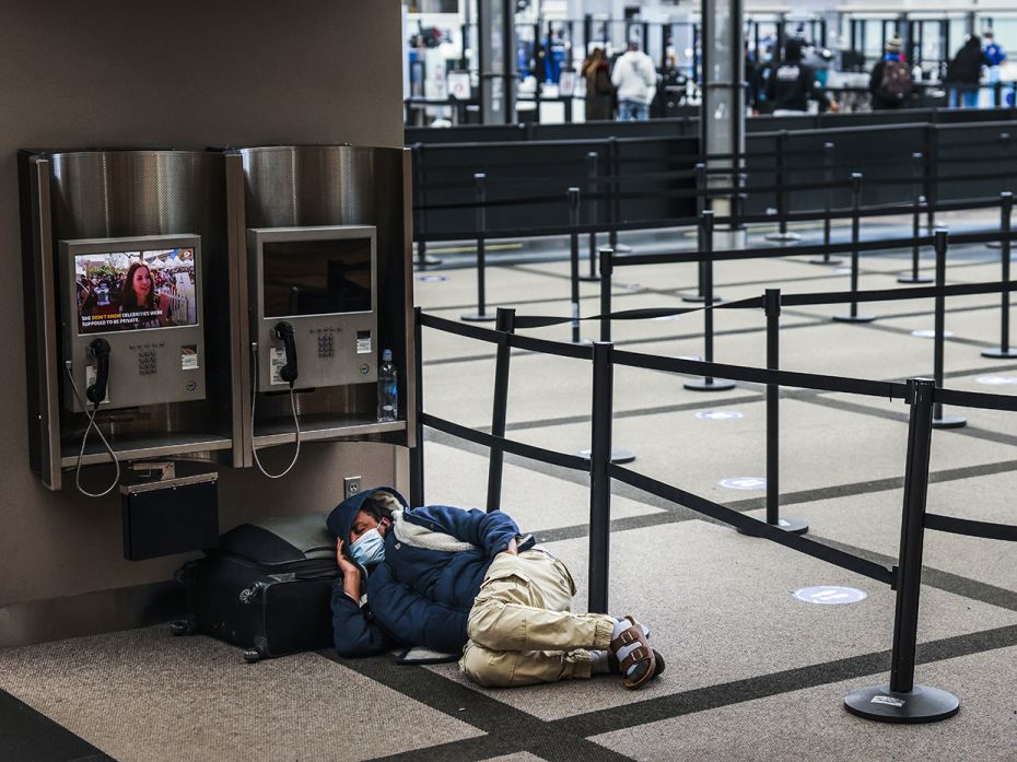 A man takes a nap next to an empty security line at Denver International Airport on March 13, 2021, 