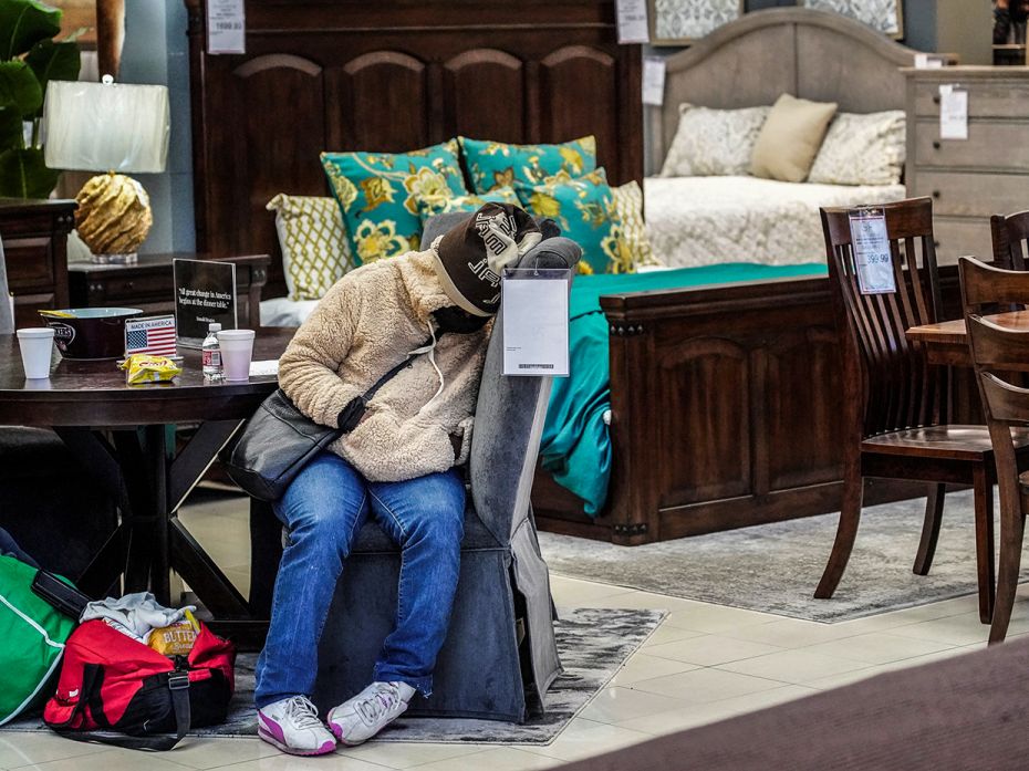 A person sleeps on a chair while taking shelter at Gallery Furniture store which opened its door and