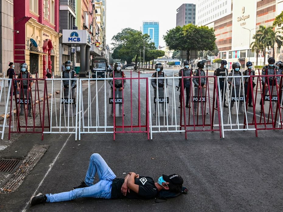 A man sleeps as police block a road where protesters used to gather against the military coup in Yan