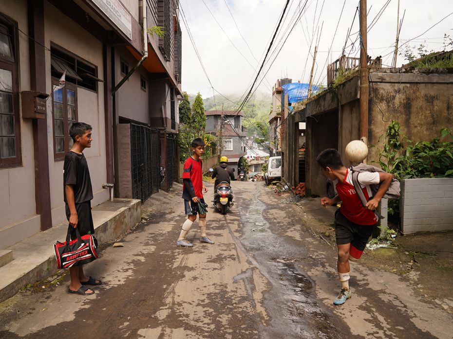 Students of Chaltlang Higher Secondary School play football in the streets on their way home in Aiza