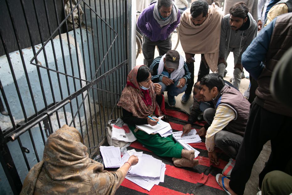 Unfazed by the crowding around her, Kanta Kirshanpal, a school teacher, helps the locals confirm the