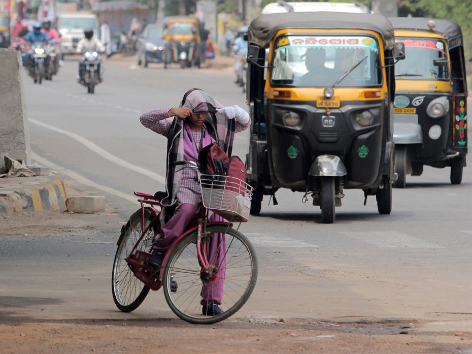 A student prepares herself to journey on her cycle by covering her face and head to protect herself 