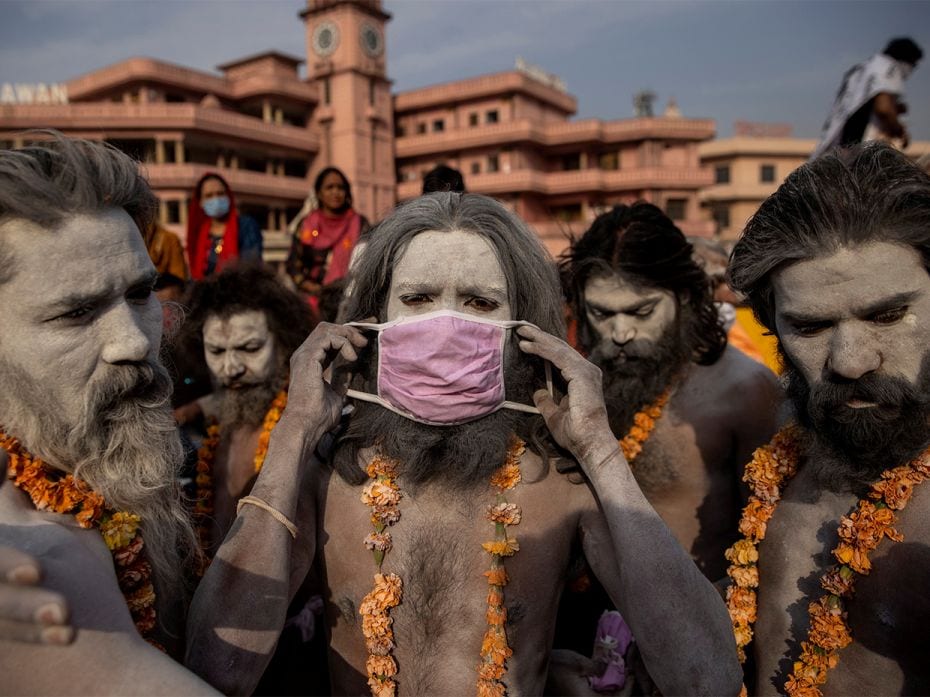 A 'Naga Sadhu,' or Hindu holy man, places a mask across his face before entering the Ganges river du