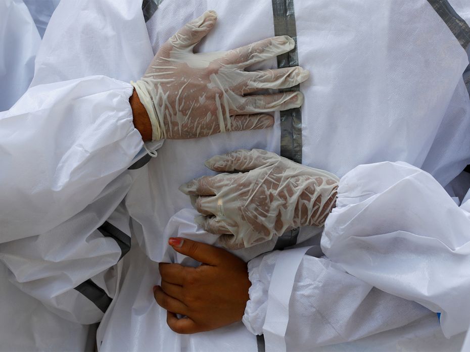 Relatives wearing personal protective equipment (PPE) mourn a man, who died from Covie-19, during hi