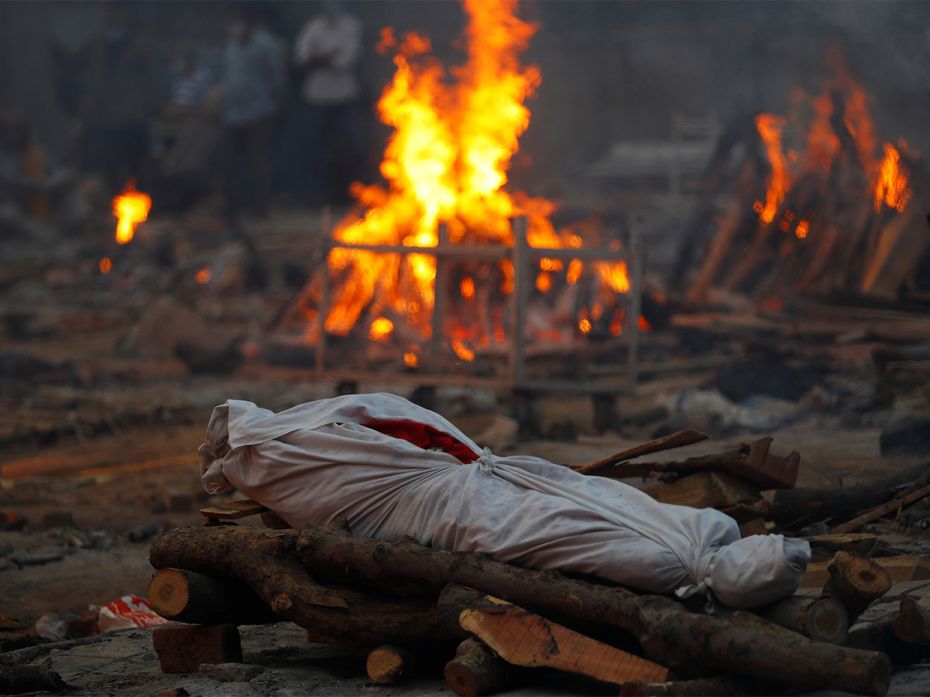 The body of a person, who died from Covid-19, lies on a funeral pyre during a mass cremation, at a c