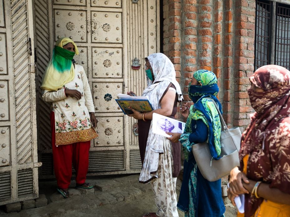 ASHA workers Nirmala, Alka, and Meenakshi talk to a resident during a door-to-door survey after the 