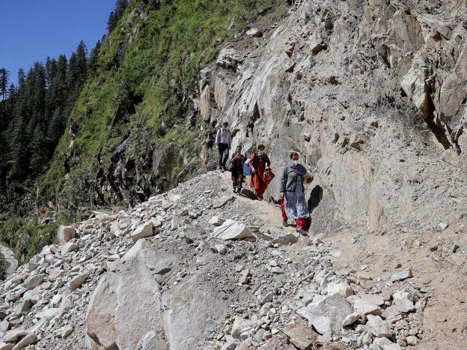 Leaving their vehicle behind upon finding the road blocked by a landslide, healthcare workers—