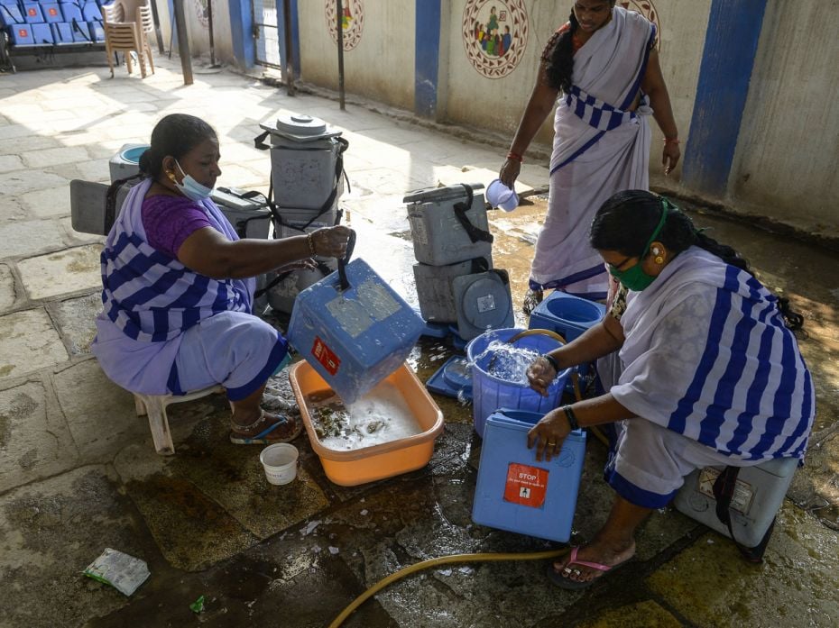 ASHA workers clean the blue vaccine carriers used for vaccine transport at a primary health centre i