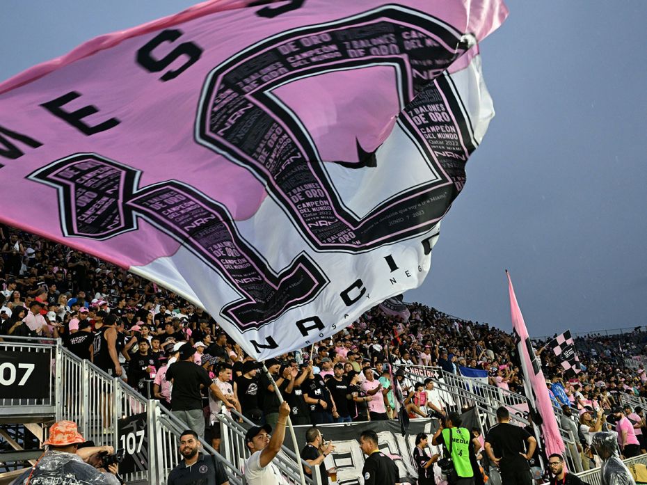 An Inter Miami club flag envelops a rapturous crowd in pink as they greet Messi at DRV PNK Stadium i