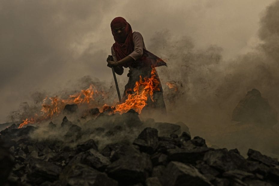 A girl burns raw coal to convert it for domestic use near an open cast mining site on the outskirts 