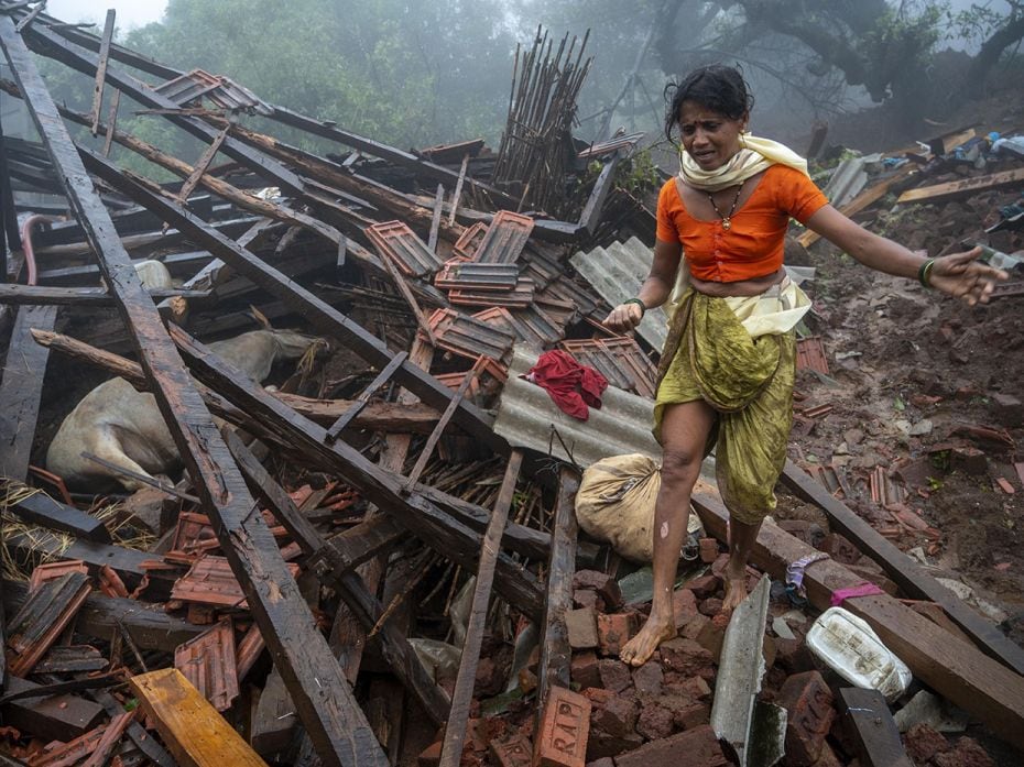 A distressed Ragi Pardhi walks about the remains of her Irshalwadi village buried under a severe lan