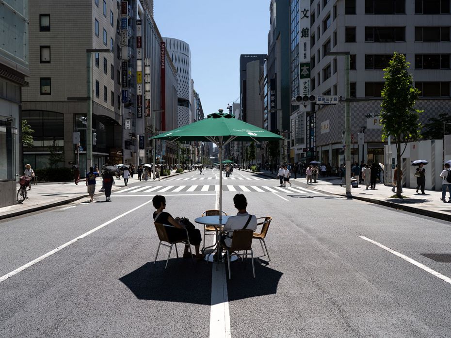 A couple rests under a parasol at the heart of the Ginza district on July 17, 2023, in Tokyo, Japan.