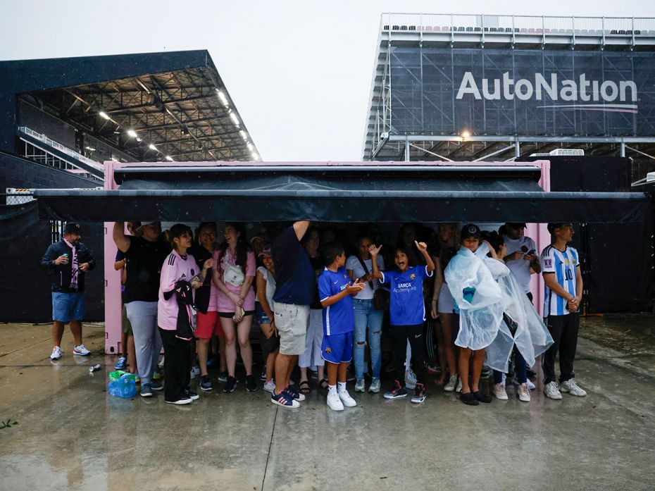 Fans shelter from the torrential rain outside Inter Miami's DRV PNK Stadium in Fort Lauderdale, Flor