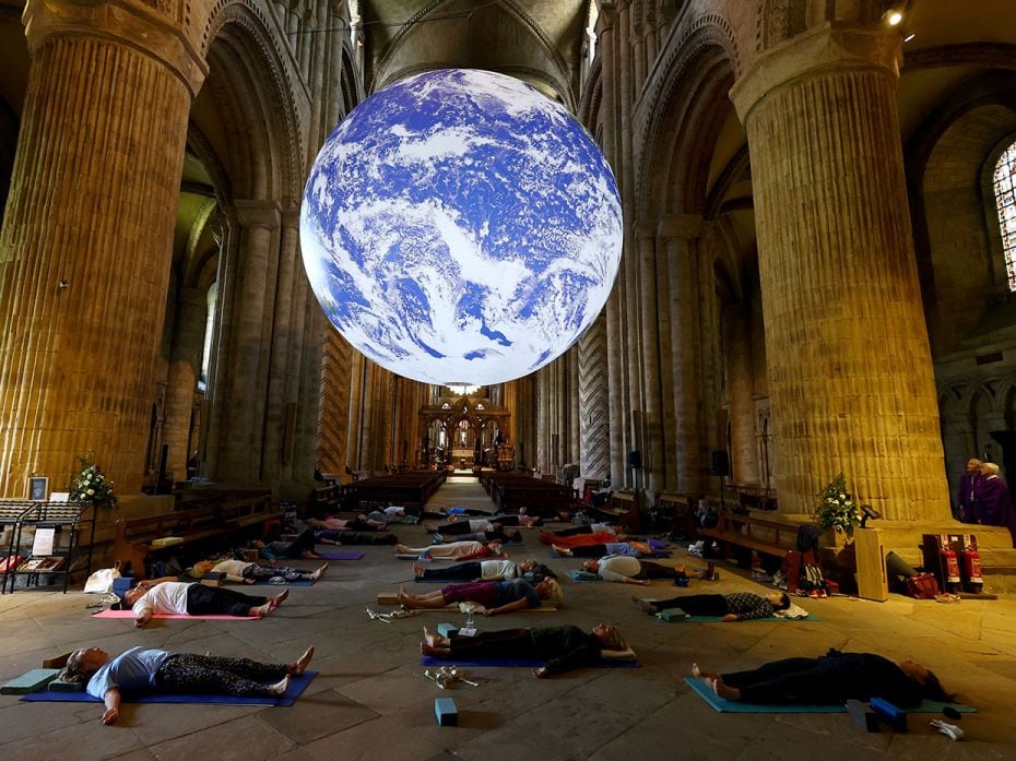 People participate in the Iyengar Yoga Class underneath Luke Jerram's Gaia artwork at Durham Cathedr