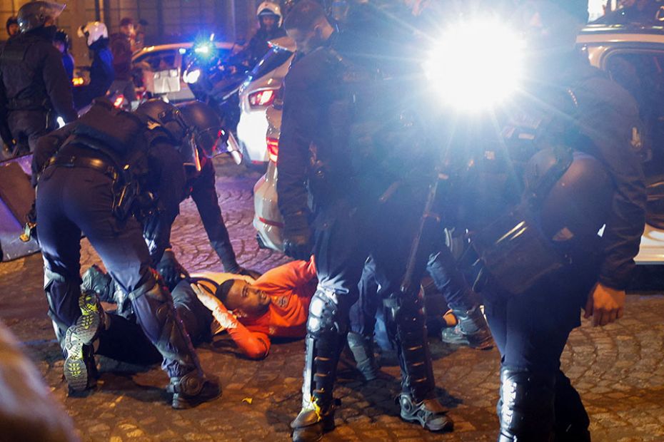 Police hold down young people during the fifth night of protests in the Champs Elysees area in Paris