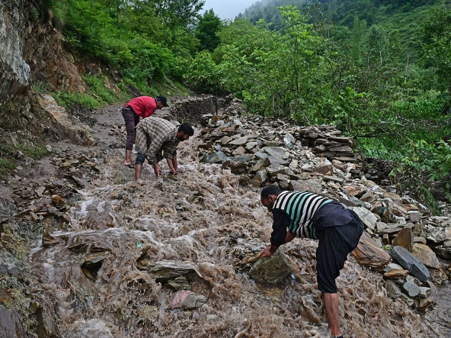 Villagers pile rocks and boulders to stop floodwaters from entering their field following flash floo