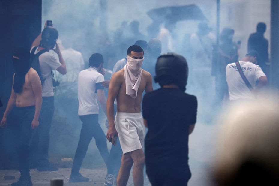 Masked protesters walk amid tear gas during clashes at a march in tribute to Nahel in Nanterre, Fran