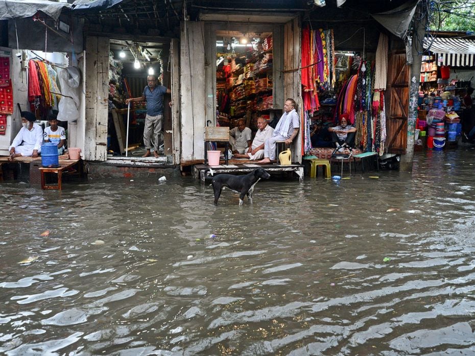 Traders crouch in their tiny shops at a water-logged market after heavy rains in Jalandhar, Punjab, 