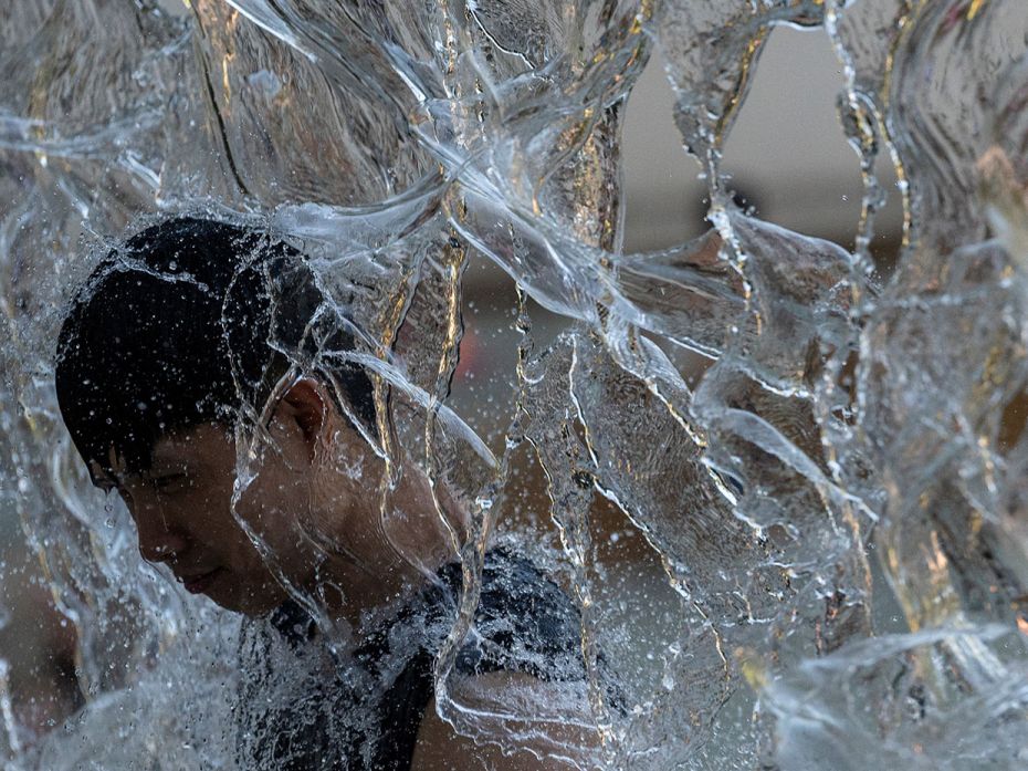 A man cools off in a public water playground at a park as temp hits a near-record high in eastern To