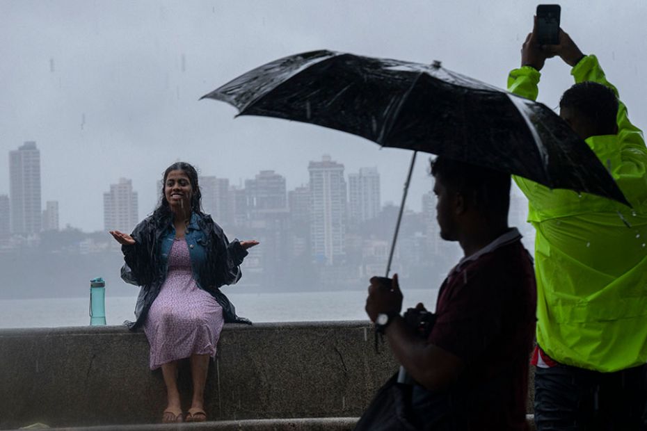 Pedestrians enjoy the rain at Marine Drive on June 25, 2023, in Mumbai, India. According to IMD, the