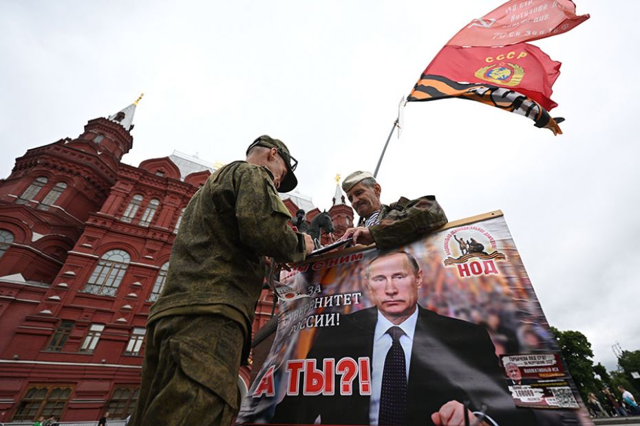 Activists hold a portrait of Russian President Vladimir Putin near Red Square in Moscow on June 24, 